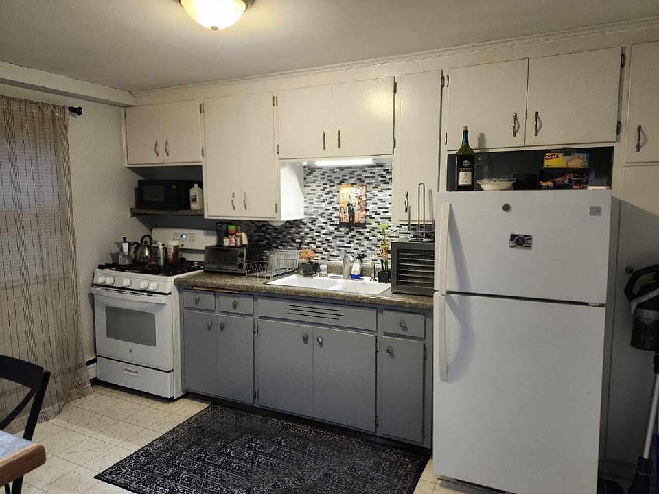 Enjoy cooking in this charming white kitchen, featuring stylish blue accents that add a fresh pop of color. The space is equipped with a newer fridge and stove.