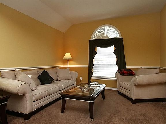 A formal living room has high ceiling, window coverings