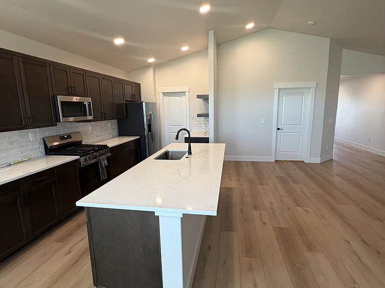 The modern kitchen is thoughtfully designed with upgraded appliances, stunning quartz countertops, and an expansive pantry that provides exceptional storage space.