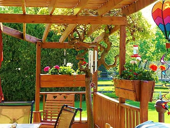 Beautiful deck with planters and pergola shading lead to inground pool