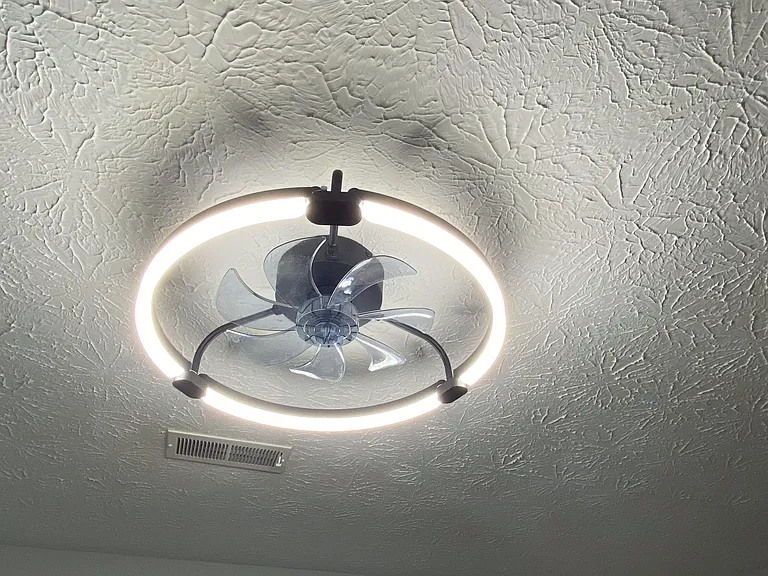 Ceiling view featuring a modern ring light fixture with integrated fan and textured finish.