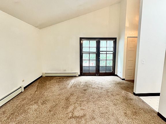 Bright and spacious living room with plush carpet and French doors leading to a serene outdoor view.