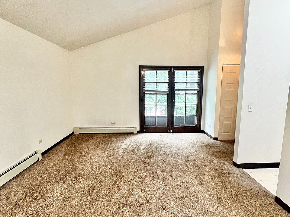 Bright and spacious living room with plush carpet and French doors leading to a serene outdoor view.