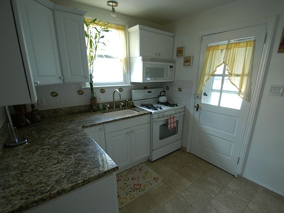 Cheerful kitchen featuring well crafted cabinetry, ceramic tile floor, garbage