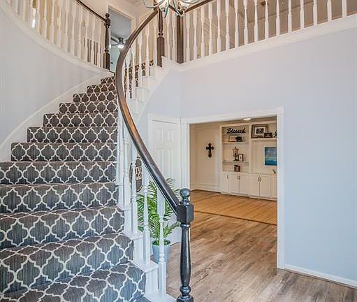Designer carpet, petina chandelier, along with white and black railings overlook the foyer giving it a double-dose of glam and country chic flair.