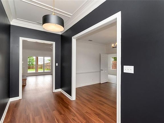 Foyer entrance featuring dark wood-type flooring, ornamental molding, and baseboards