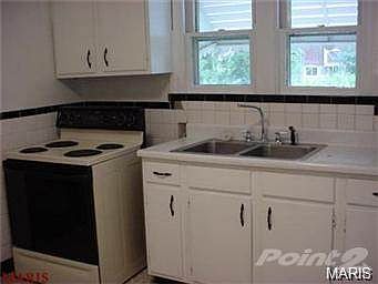 Kitchen has electric stove/range and white cabinets.