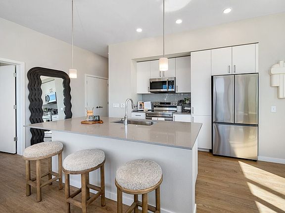 Finish Scheme I kitchen with grey quartz countertops, white cabinetry, grey subway tile backsplash, stainless steel appliances, and hard surface flooring