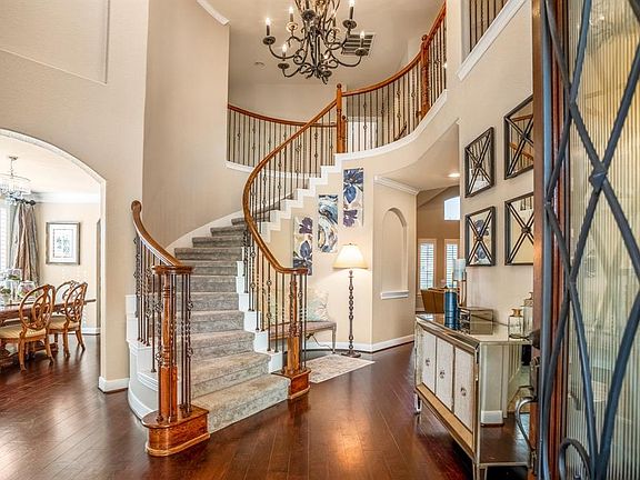 Incredible front door leads to an entry and stunning foyer with gleaming wood flooring and wrought iron spindles on spiral staircase.
