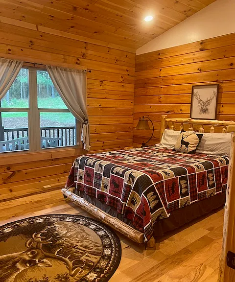 Second bedroom has a queen size bed, one nightstand with one lamp, one dresser with 5 drawers, round area rug, deer sketch over bed, nice size closet. Faces front of cabin