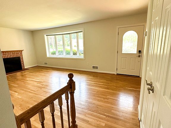Living room with beautiful hardwood flooring, bow window bringing in the light and woodburning fireplace.