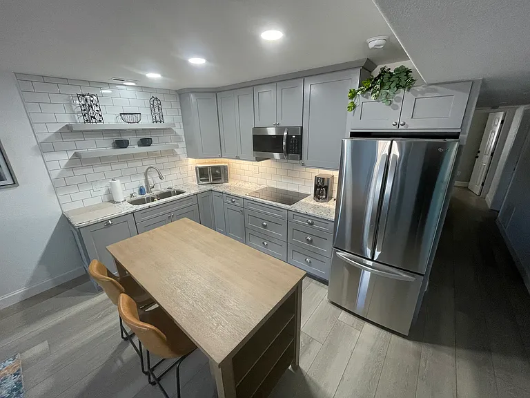 Kitchen with new granite countertop, induction stovetop, microwave, large toaster oven, and full sized fridge. Plates, pots, pans, flatwear, etc, all included.