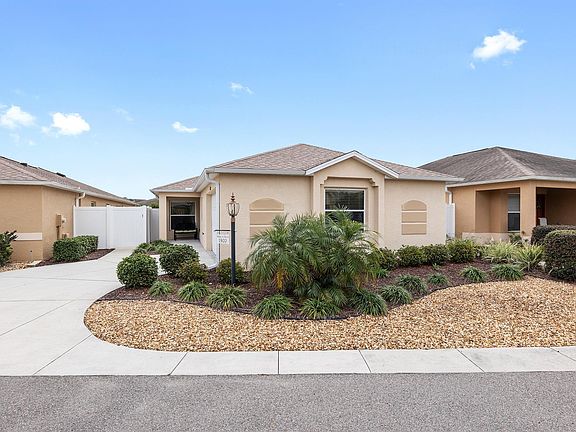 Front of house showing sitting porch with rocking chair, private driveway, and garage for one medium sized cart + a golf cart. Additional parking for guests available around the corner.