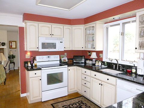 Kitchen has granite counters and distressed cabinetry