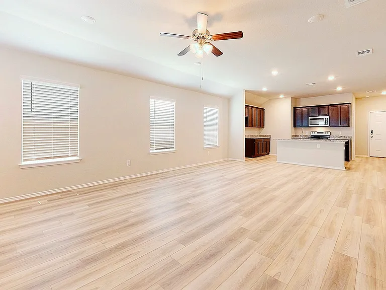 Spacious open-concept layout connecting the family room, dining, and kitchen _ filled with natural light from south-facing windows that overlook open space, with no neighbor on that side.