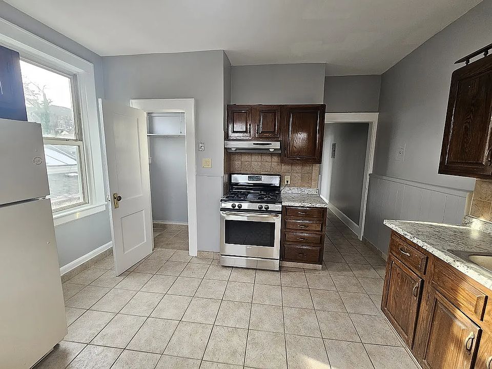 Kitchen with pantry, includes gas range and refrigerator, from doorway.