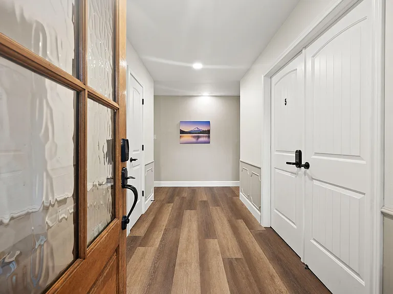 Clean entry hallway with durable wood-look flooring, recessed lighting, and secure interior doors for private room access.