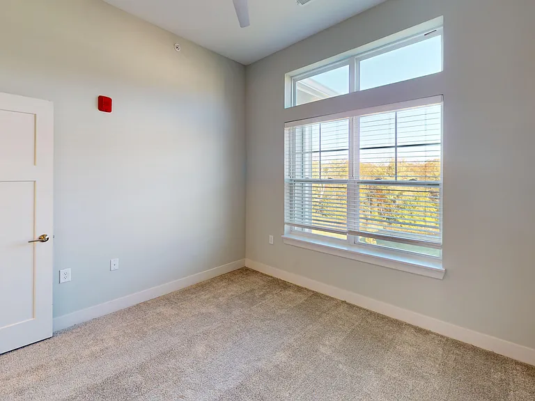 The second bedroom of The Dogwood floor plan features large windows, lush carpet, and a walk-in closet. The second bedroom of The Dogwood floor plan features large windows, lush carpet, and a walk-in closet.