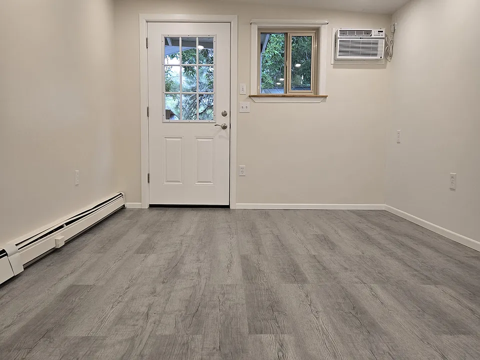 Twin, full or queen sized bed fits to the right of door. View of sliding window and A/C unit.