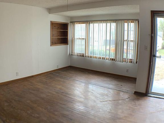 Spacious living area. Vertical blinds. Wood floors. Ceiling fan.