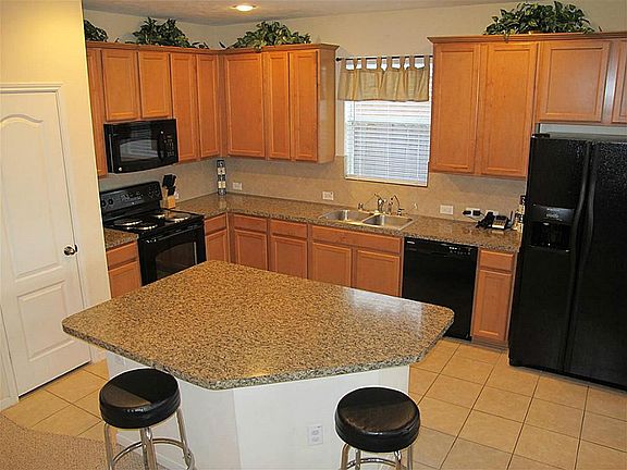 Gourment island kitchen boasts ceramic tile flooring & backsplash, abundant 42" cabinetry, black app
