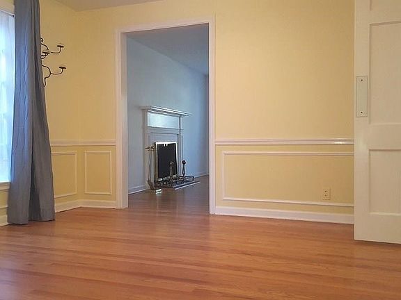 Elegant Formal Dining Room with Chair Rail, Wainscoting, and Wood Floor Opens to Kitchen, LR, and FR
