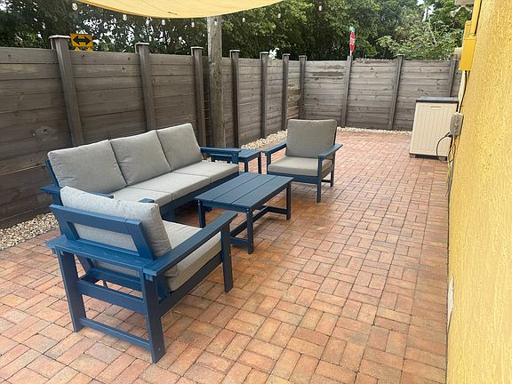 Side patio with sunshade, string lights and polywood furniture set.