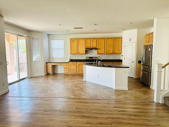 Open kitchen and family room with a large center island, stainless steel appliances, abundant natural light, and direct patio access.