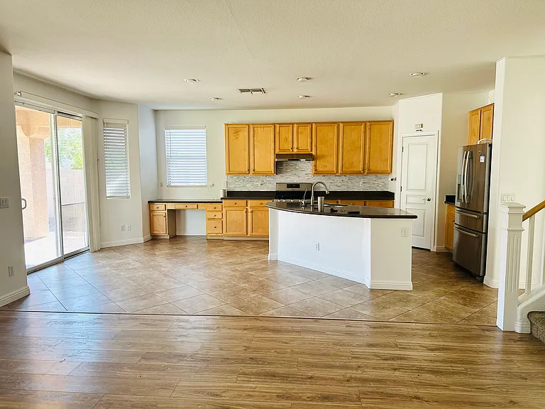 Open kitchen and family room with a large center island, stainless steel appliances, abundant natural light, and direct patio access.
