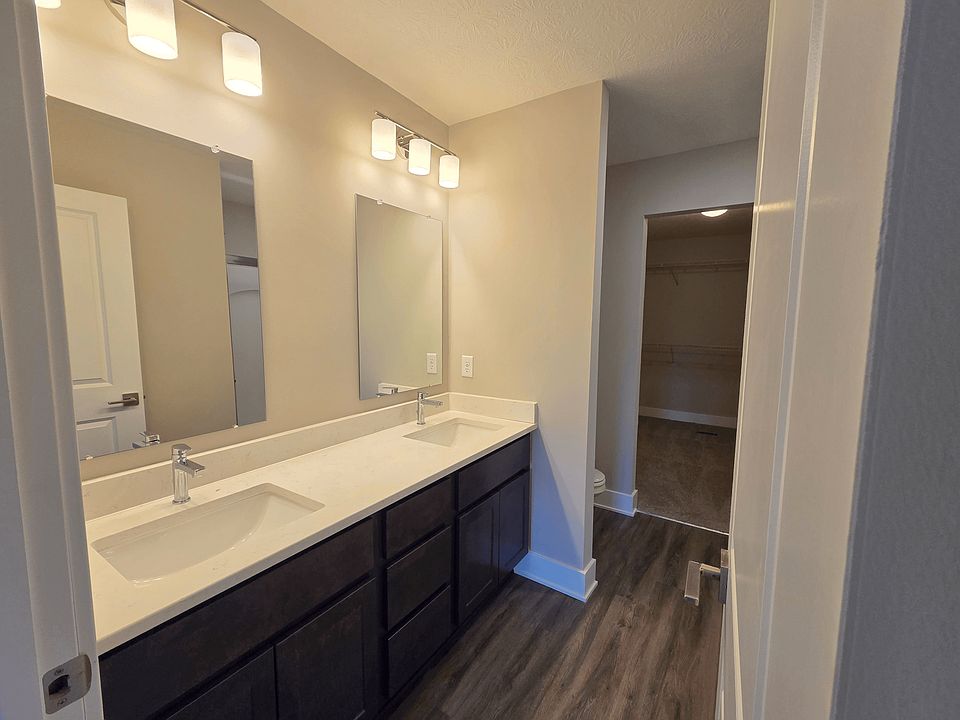 Townhome primary bathroom with dual sinks, shower, and closet.