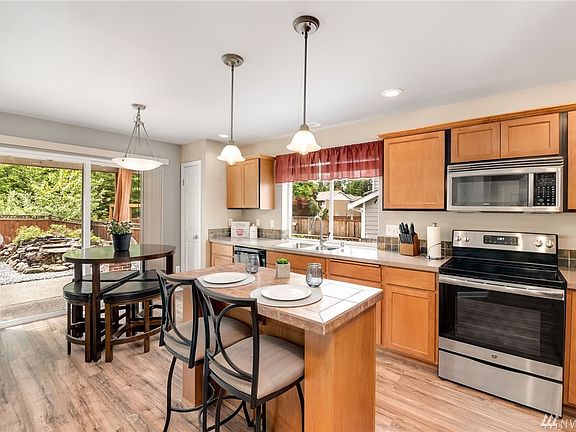 Open Kitchen with island, breakfast bar, tile backsplash, stainless appliances.