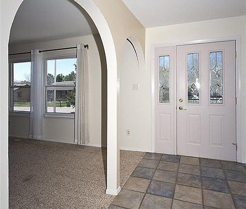 Entry door with beveled glass windows. the floor is tile, living room is to the