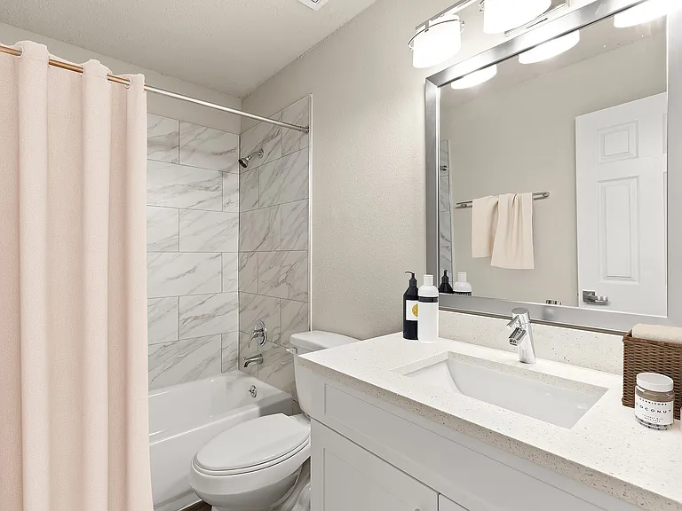 Bright and modern bathroom featuring elegant marble tiles, a stylish vanity with ample storage, and a luxurious bathtub.