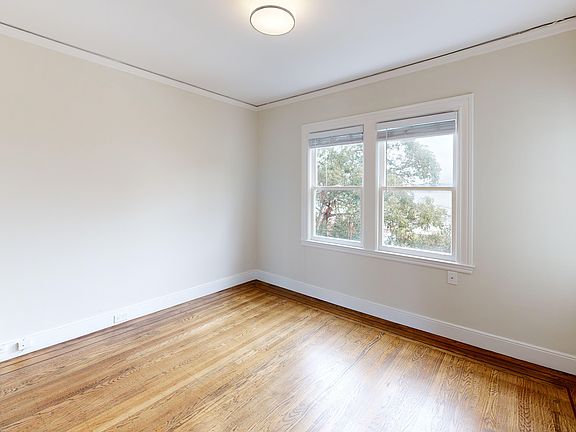 Sunlit room with a large window and wood-like flooring