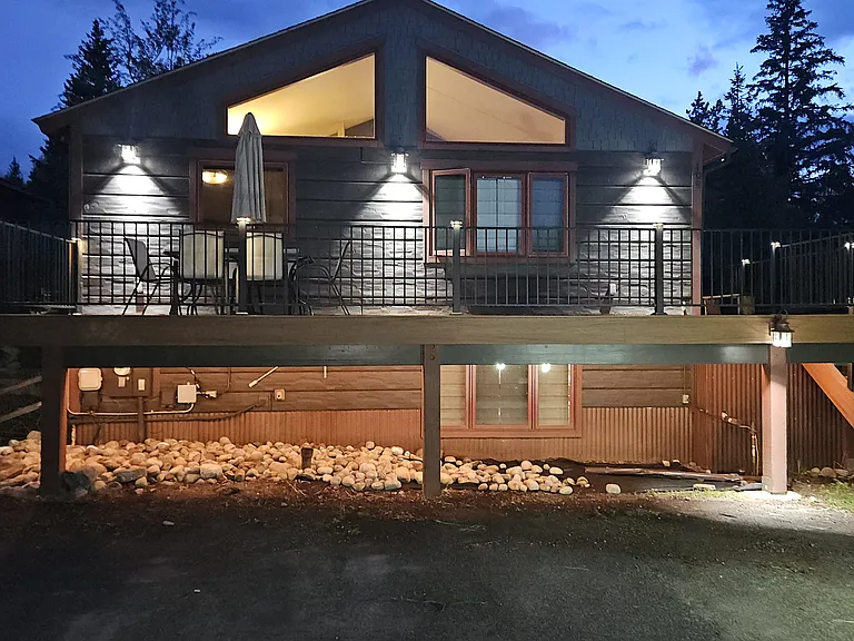 Front of house at night. Deck lights, sconces, under deck lighting. parking for 4 cars in front,