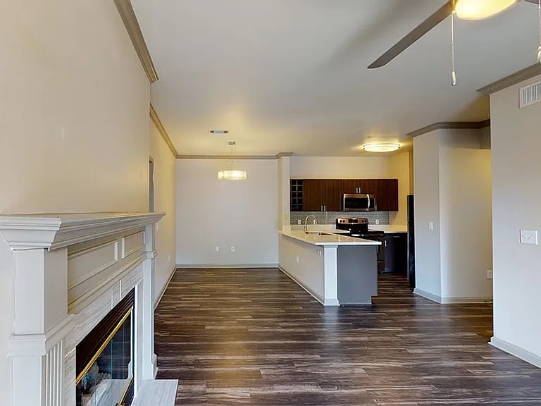 Gourmet kitchen with stainless steel appliances, dining and living room with wood-style flooring.