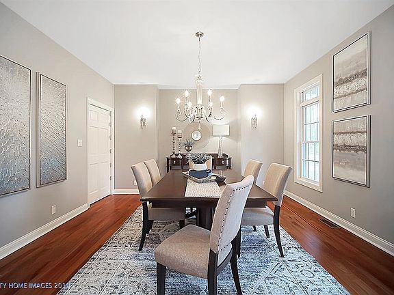 On the opposite side of the foyer resides this beautifully proportioned dining room with high ceilings, generously-sized windows with transoms, refinished hardwood floors, updated lighting fixtures, and pantry door leading to the kitchen.