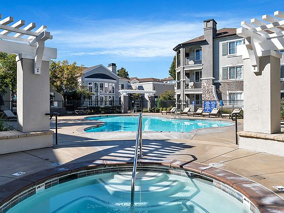 Swimming pool and spa surrounded by lounge chairs.