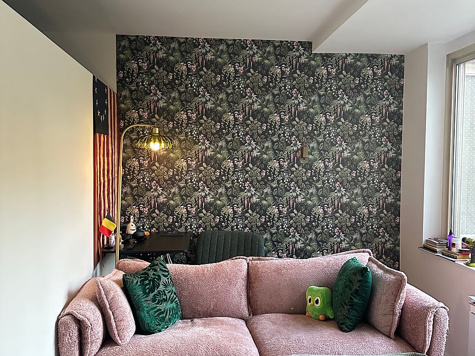 view from the dining area towards the living area- comfortable sofa, cute accent wall, classic reading lamp.
