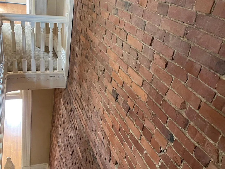 stairs from top floor looking down to main floor with living room, full bathroom and kitchen