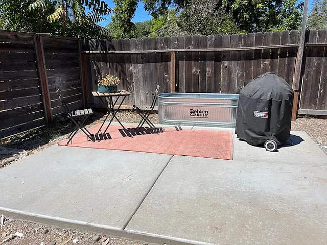 Spacious and private fenced backyard with a 10 x 12 foot concrete patio, freestanding garden bed for planting herbs, vegetable, flowers.