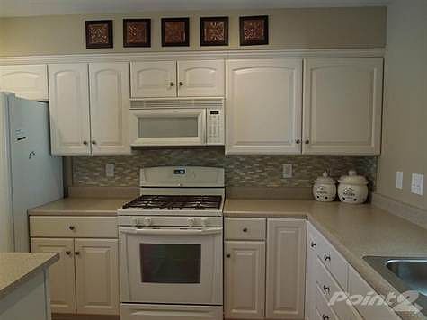 An abundance of cabinets, and counter space, gas oven/range, built-in microwave, side-by-side refrigerator, hardwood floors, and island enhance the kitchen with pass through to formal dining room.
