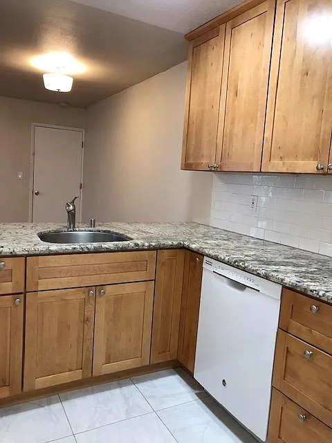 Kitchen and living/dining room with open floor plan, granite counter, maple shaker cabinets, white subway tile.
