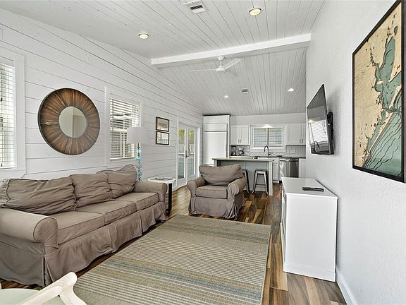 Open living/kitchen/dining space with beautiful tile (looks like wood) flooring throughout.