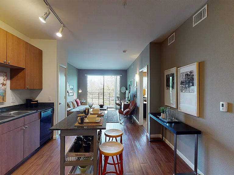 Apartment kitchen, dining and living room with wood-style flooring.