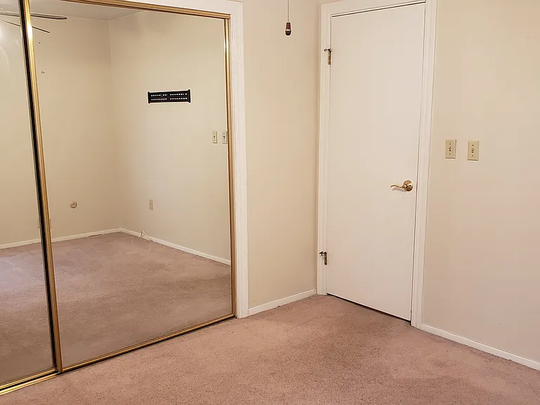 Master bedroom view showing wall -to-wall mirror doors and fan.