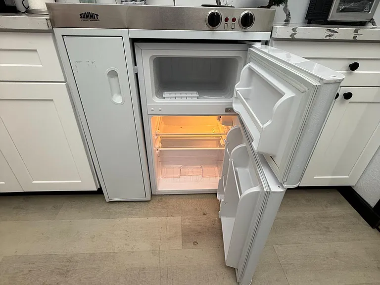 Compact kitchenette with an under-counter refrigerator/freezer, sink, and counter space for daily meal prep.