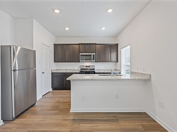 Designer kitchen with granite countertops, stainless steel appliances, and wood-style flooring.