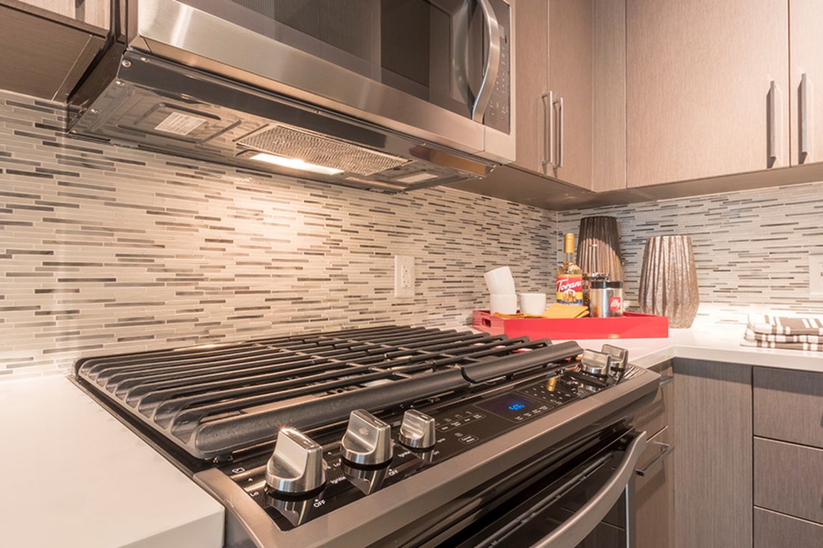 Designer inspired backsplash, under cabinet lighting and gas cooktops