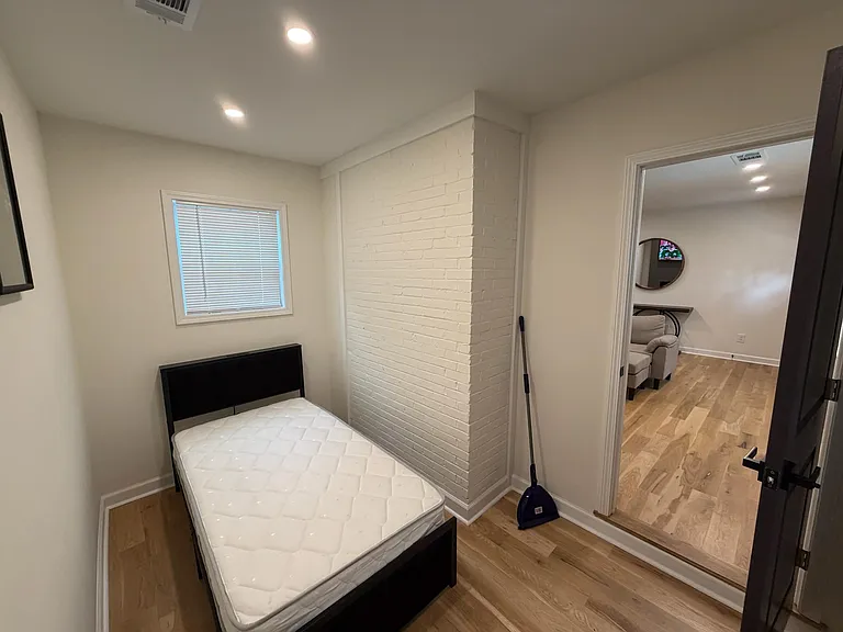 Private bedroom with a bed frame and mattress, a window with blinds, and easy access to the adjacent common area.